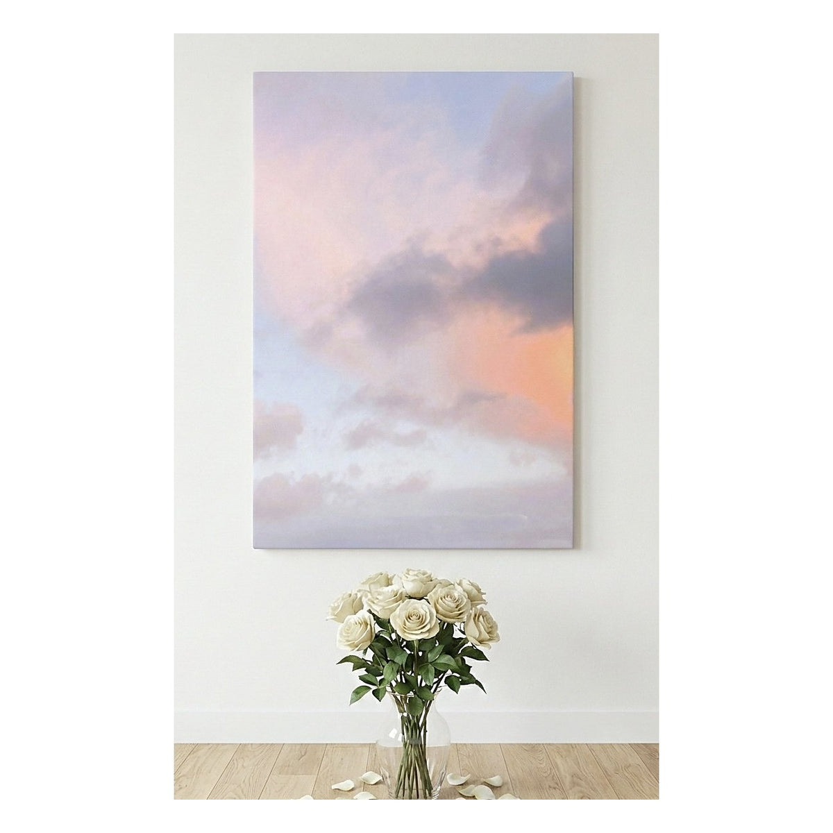 A vertical canvas wall art print depicting a pastel sky with pink, lavender, and peach clouds, displayed on a white wall above a vase of white roses on a light wood floor.