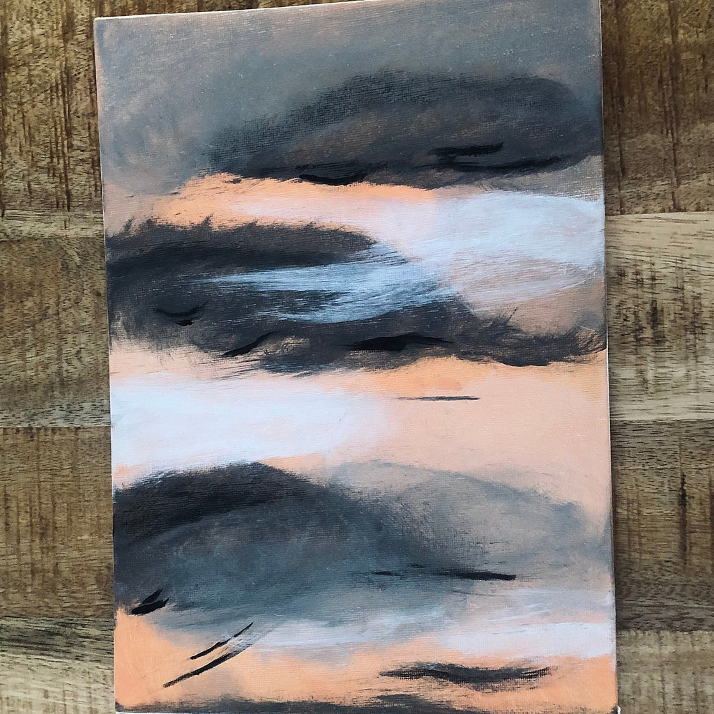 An abstract emotional art print landscape painting on canvas featuring dark charcoal and slate blue clouds over a soft peach and light blue sky, displayed on a rustic wooden background.