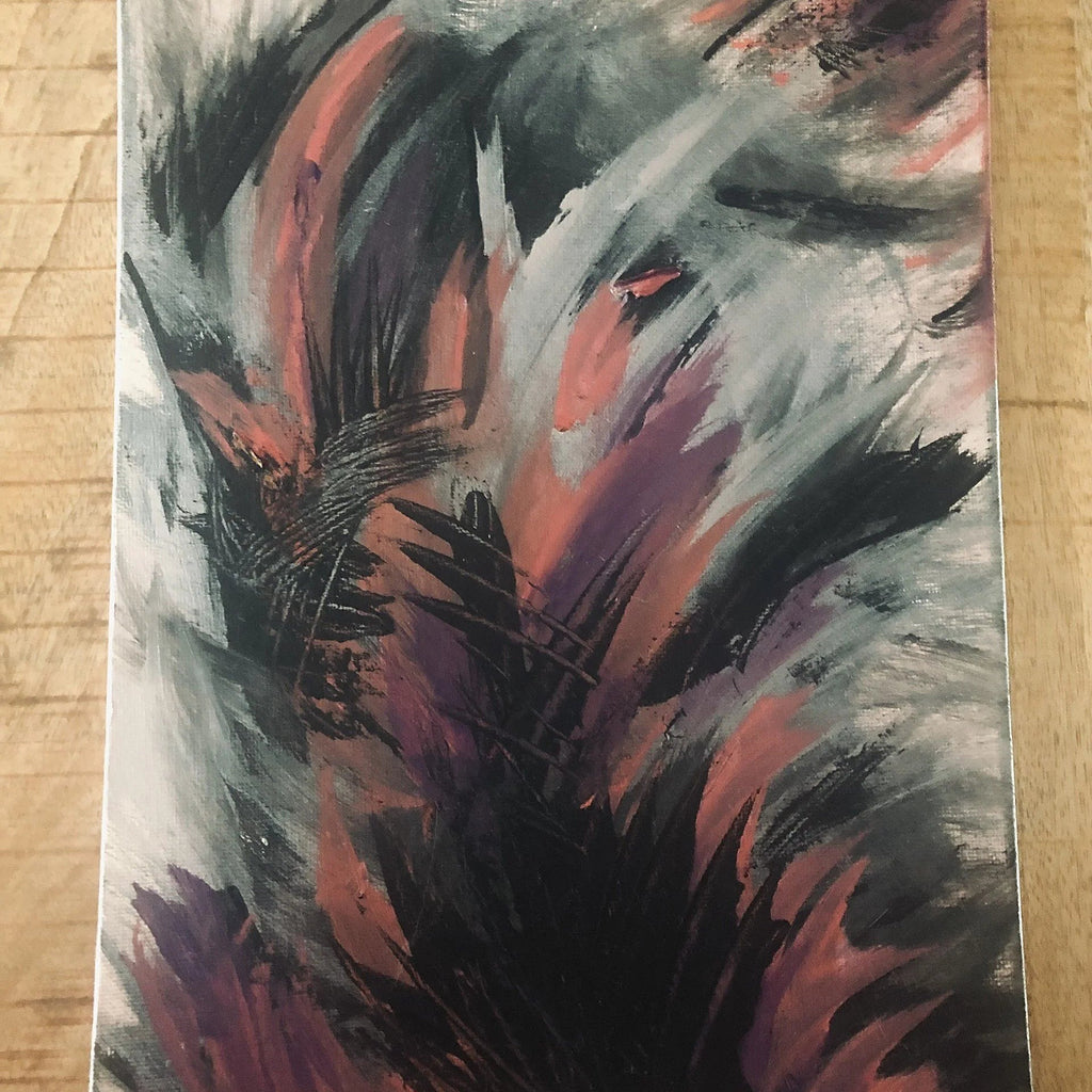 An abstract emotional canvas print painting featuring expressive brushstrokes in black, gray, white, and reddish-pink tones, photographed flat on a light wood surface.