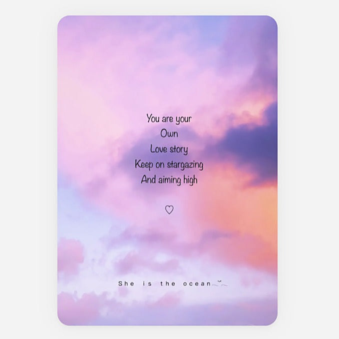 A rectangular art print greeting card with rounded corners featuring a pastel purple, pink, and blue cloudy sky background. Centered black quote reads, 'You are your Own Love story Keep on stargazing And aiming high' with a small heart below, and smaller text at the bottom reads 'She is the ocean.