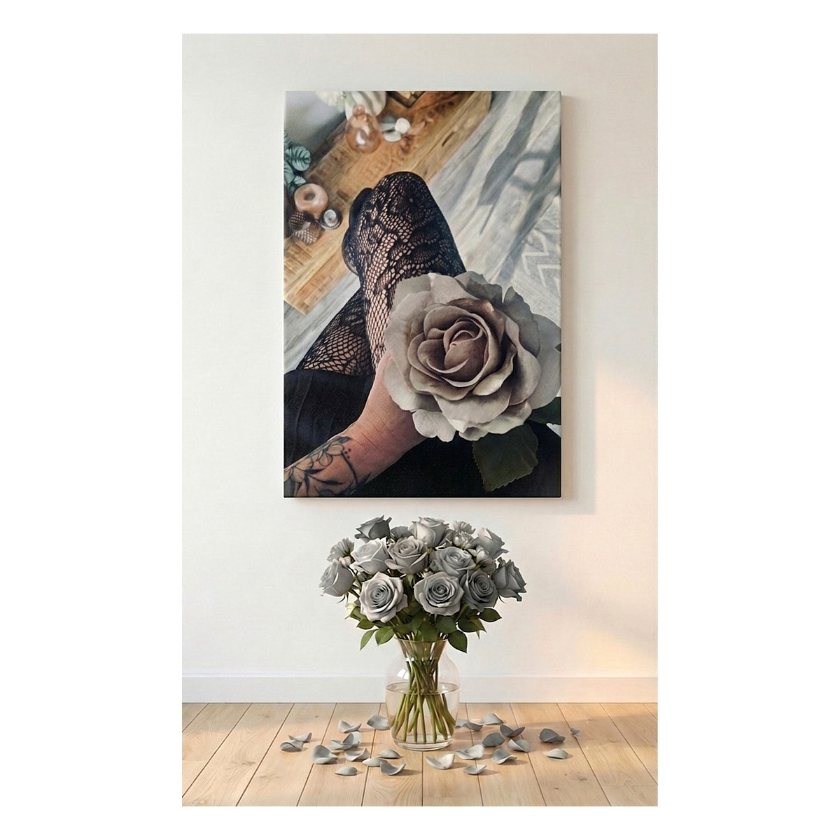 A vertical canvas artwork wall art print showing a close-up of a tattooed hand holding a large gray rose, displayed above a bouquet of gray roses on a light wood floor against a white wall.
