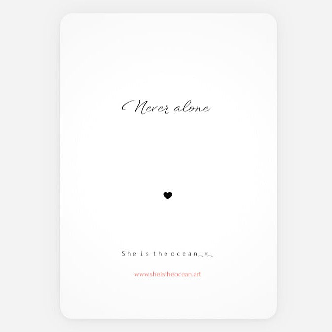 A minimalist white art print greeting card with rounded corners, featuring the quote 'Never alone' in black cursive, a small black heart, and additional text 'She is the ocean' with a small red website URL at the bottom.