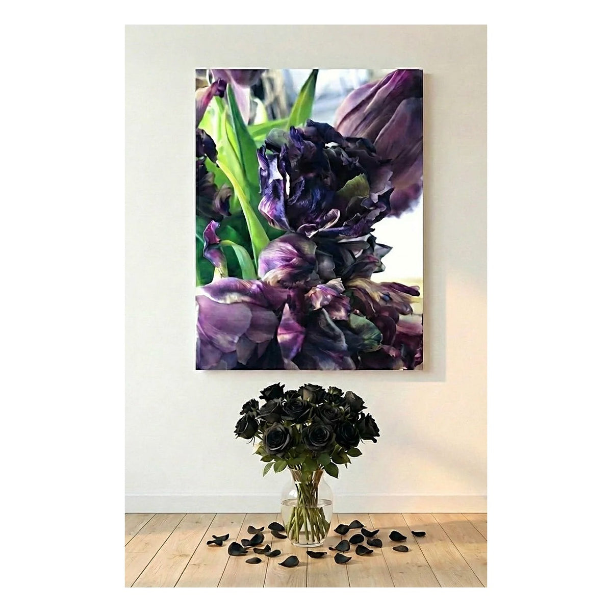 A vertical canvas wall art print depicting dark purple tulips, displayed on a light beige wall above a floor arrangement of black roses and scattered petals.